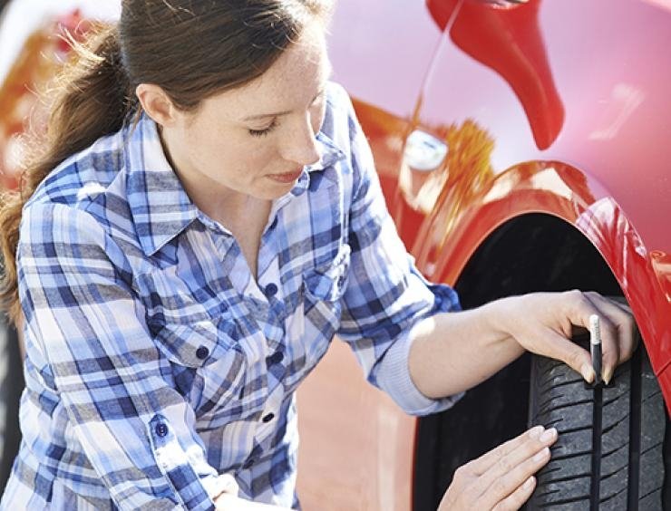 uma mulher está a mudar o pneu de um carro vermelho
