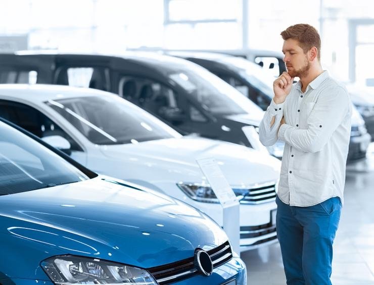 um homem em pé em frente a uma fila de carros estacionados